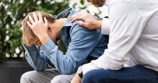 Upset young adult male sits outside with his d